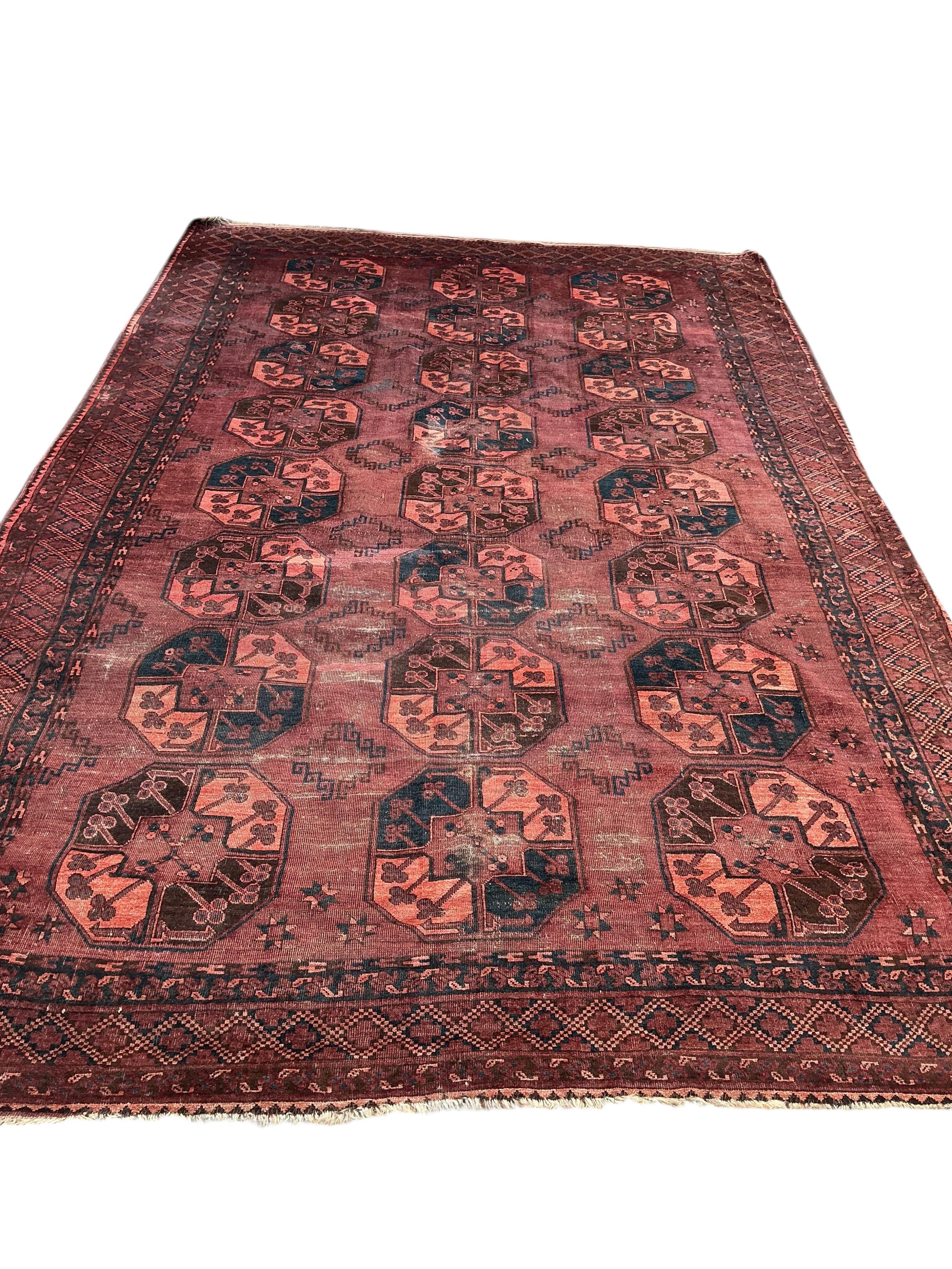 An Afghan burgundy ground carpet, 375 x 230cm